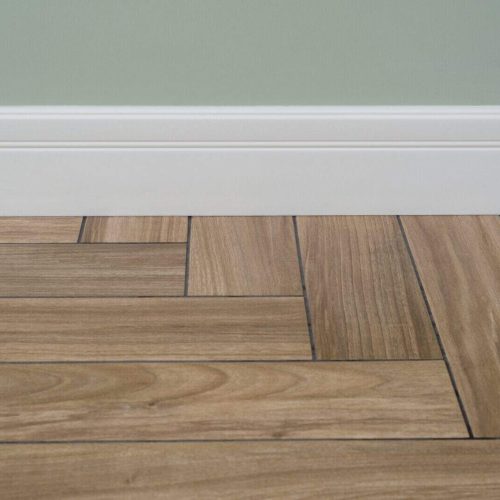 Interior concept. Light matte wall, white baseboard and tiles immitating hardwood flooring