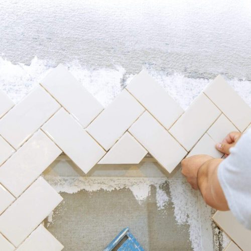 Troweling mortar into the hands of laying the tiles the ceramic tile